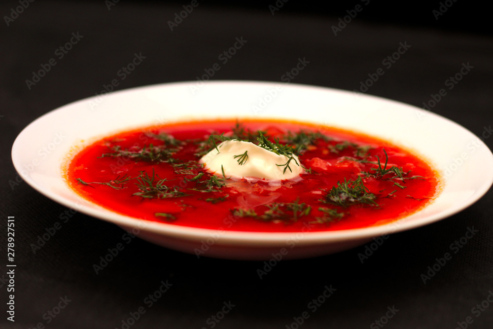 Bowl of beet root soup borscht with sour cream and greens isolated on black canvas with dark background Bowl of beet root soup borscht with sour cream and greens isolated on black canvas with dark background