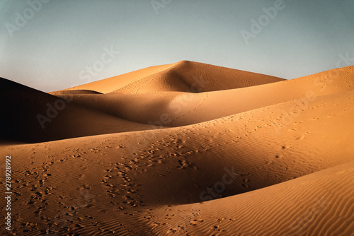 Düne in der Sahara Wüste mit Fussspuren von Dromedaren und Menschen mit bewölktem Himmel in Marokko photo