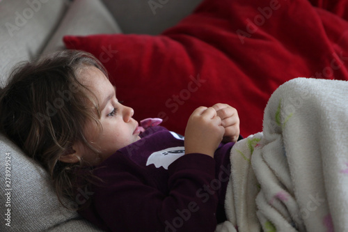 A three year old girl relaxes on the sofa