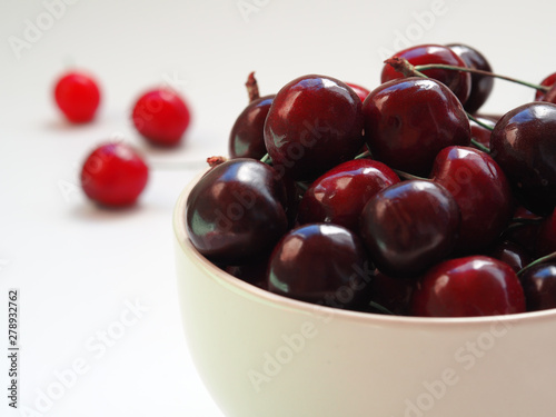 red cherry in a white bowl on a white background. Summer fruits and vitamins.