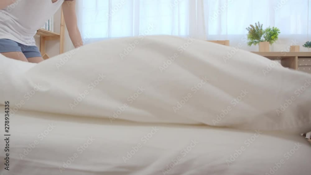 Asian woman cleaning her bed in bedroom, Beautiful japanese female set up and making bed blanket at home. Lifestyle women using time cleaning home concept. Slow motion shot. Asian woman cleaning her bed in bedroom, Beautiful japanese female set up and making bed blanket at home. Lifestyle women using time cleaning home concept. Slow motion shot.