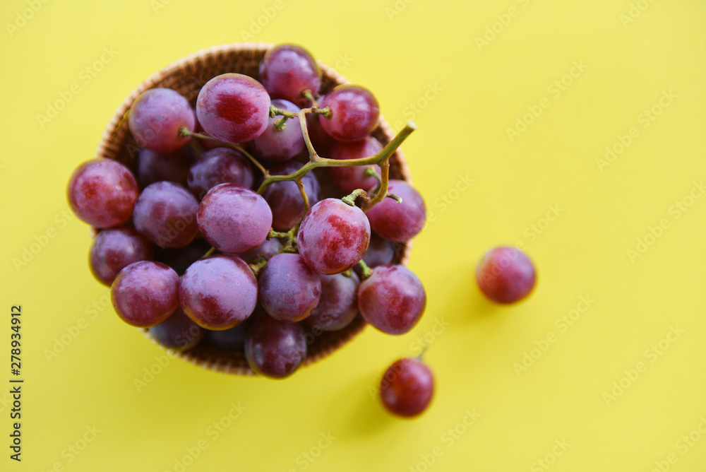 Red grape bunch in basket - Fresh grape fruit on the table with yellow background