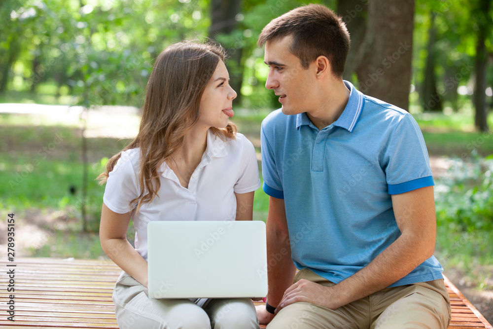 A guy and a girl are reading a book in a city park on a hot summer day. A guy and a girl are reading a book in a city park on a hot summer day.