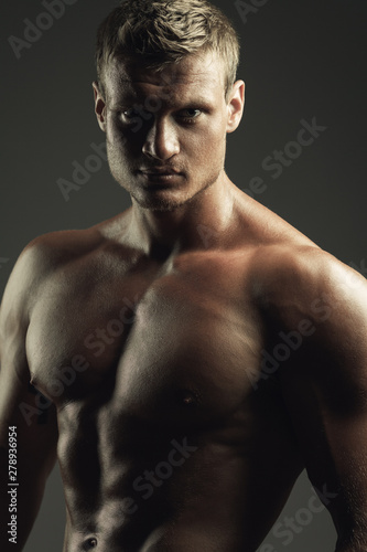 Bodybuilding and body sculpture concept. Beautiful (handsome) muscular male model with blond hair, perfect body posing over gray background. Close up. Studio shot