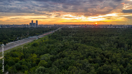 Fototapeta Naklejka Na Ścianę i Meble -  Flying over the trees of a large city Park towards the sunset