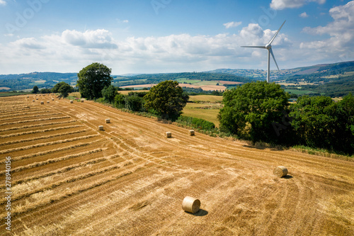 Aerial view of Straw bales with a wind turbine on farmland in Wales UK