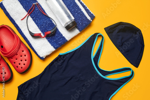 Flat lay summer pool accessories on a yellow background. Colorful beach wear.