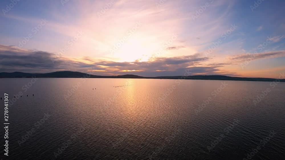 Aerial view on calm sea water during colorful Sunset with mountain on background Aerial view on calm sea water during colorful Sunset with mountain on background