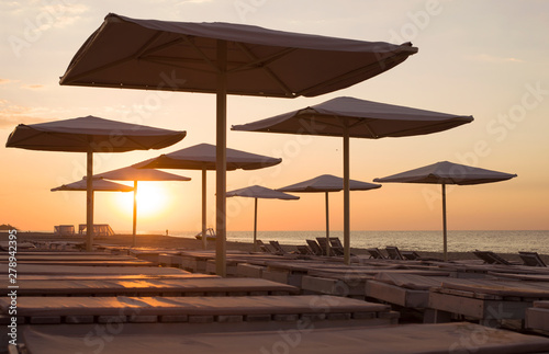 Fototapeta Naklejka Na Ścianę i Meble -  Silhouettes of beach umbrellas in the background of  sunrise