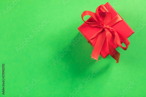 Red square gift box with a bow on a green background