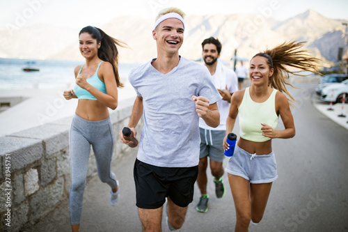 Happy fit people running and jogging together in summer sunny nature