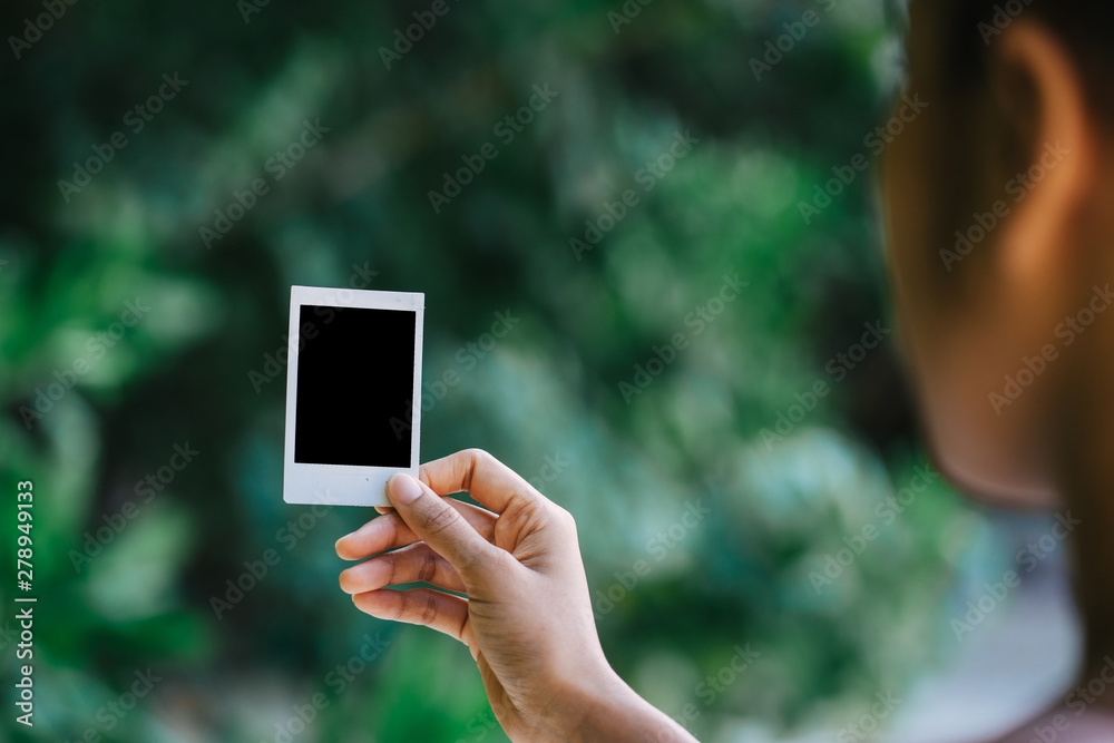 Woman holding blank instant photo frame on the beach.