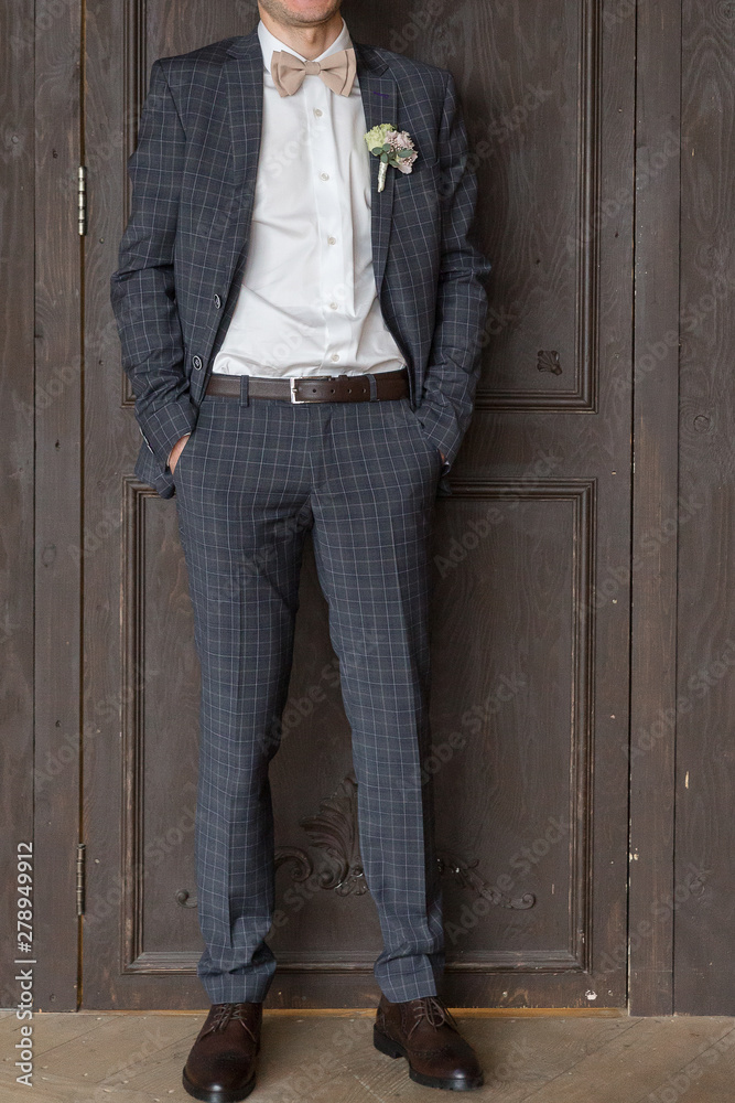 men's suit deuce with checkered pattern in monochromatic gray. Tie, butterfly, shoes. The image of wealthy male businessman, groom, presenter, showman men's suit deuce with checkered pattern in monochromatic gray. Tie, butterfly, shoes. The image of wealthy male businessman, groom, presenter, showman