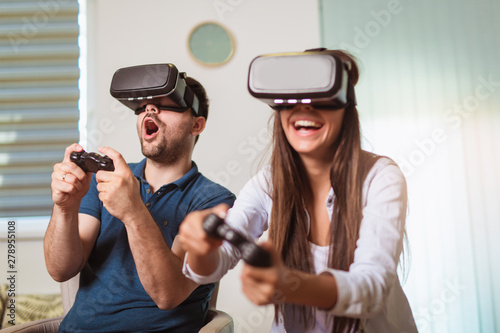 Young happy couple playing video games virtual reality glasses. Couple having fun with new trends technology.