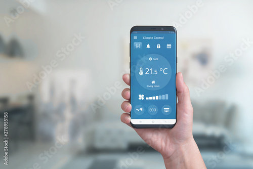 Smart phone in hand with climate control app. Concept of environmental comfort automation with a simple phone app.