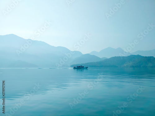 Fototapeta Naklejka Na Ścianę i Meble -  Large blue lake with lonely ship in the morning