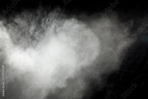White powder explosion on black background. Abstract white dust texture fly on the air.