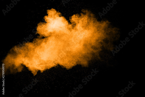 Abstract orange dust explosion on black background. Freeze motion of orange powder clouds splash.