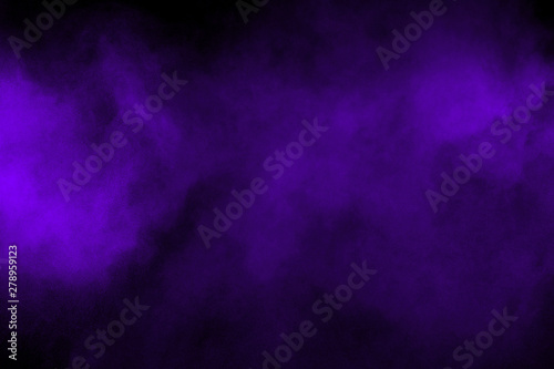 Freeze motion explosion of purple powder dust on a black background. By throwing blue talcum out of hand. Stopping the movement of purple powder on dark background.