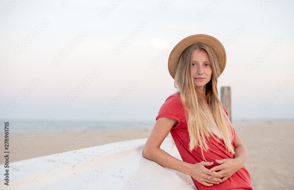 Beautiful woman with long hair wear straw hat on the beach near wooden boat. Beautiful woman with long hair wear straw hat on the beach near wooden boat.