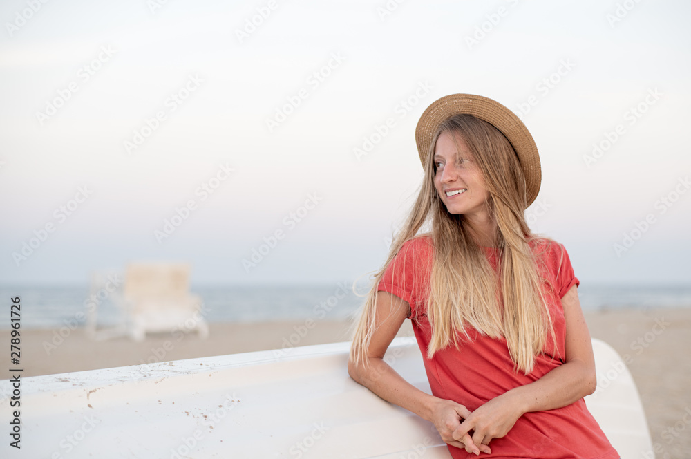 Beautiful woman with long hair wear straw hat on the beach near wooden boat.