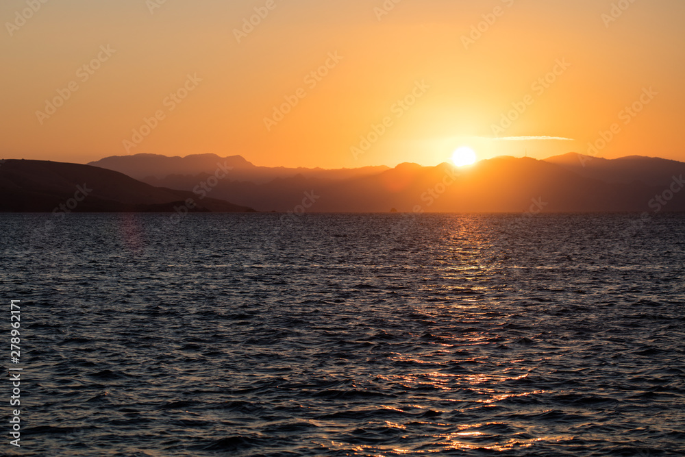 A beautiful sunset occurs in Komodo National Park, Indonesia. This remote region, part of the Coral Triangle, has high marine biodiversity and is a popular destination for divers and snorkelers.
