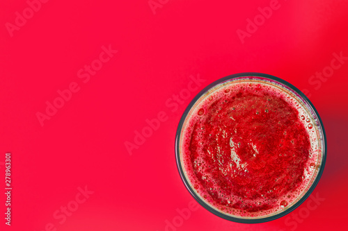 Glass with red beet berries and fruits smoothie from strawberries raspberries currants bananas apples on same color background. Healthy vegan lifestyle detox vitamins plant based diet concept