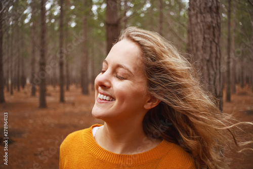 Smiling young woman enjoying the fresh air in the forest