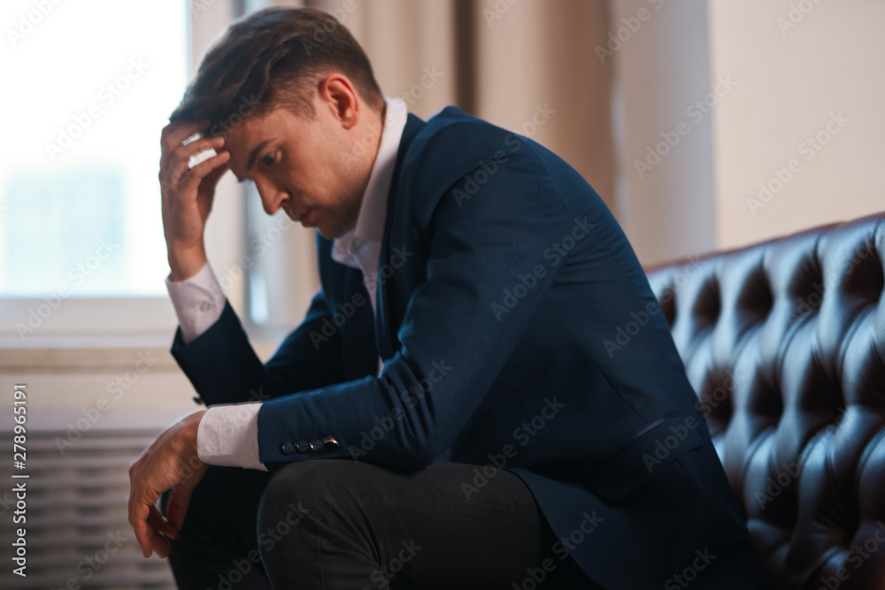 Fototapeta premium man sitting on sofa and talking on cell phone