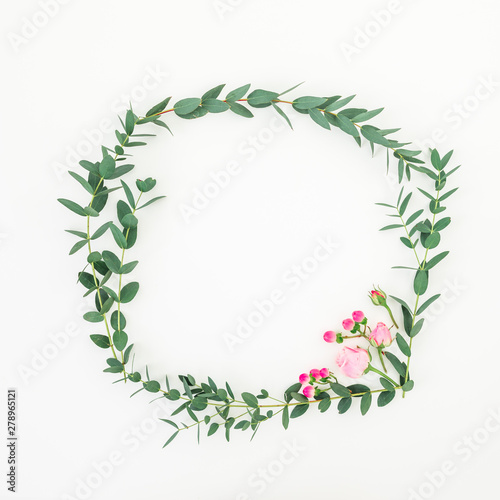 Floral wreath frame made of pink roses and eucalyptus branches on white background. Flat lay  top view