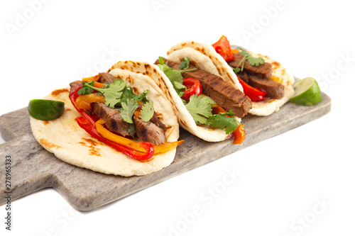 Three Fajitas on a Marble Serving Board on a White Background