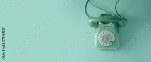 A green vintage dial telephone with green background.	