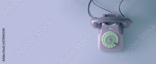 A violet vintage dial telephone with violet background.