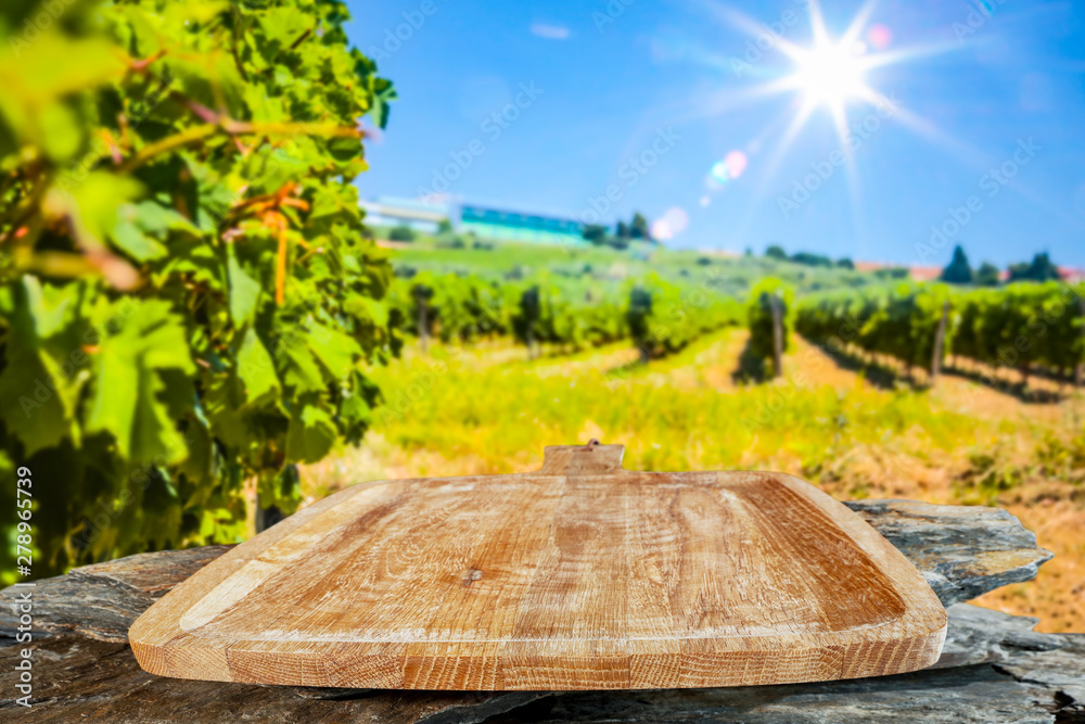 A wooden cutting board and tray background in the beautiful sunny vineyard view A wooden cutting board and tray background in the beautiful sunny vineyard view