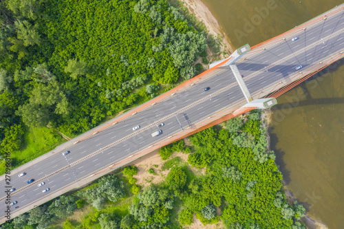 City car moving at highway bridge on background smooth river surface drone view. Aerial view
