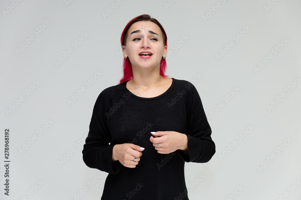Portrait to the waist of a pretty girl with red hair on a white background in a black jacket. Standing right in front of the camera in a studio with emotions, talking, showing hands, smiling Portrait to the waist of a pretty girl with red hair on a white background in a black jacket. Standing right in front of the camera in a studio with emotions, talking, showing hands, smiling