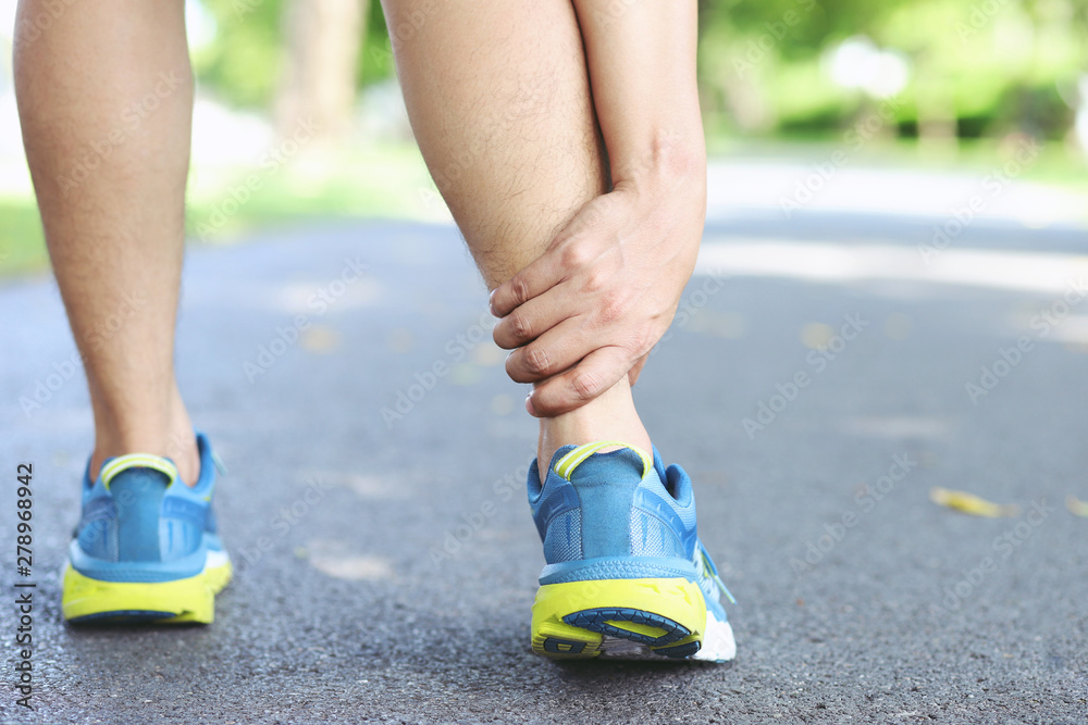 Runner touching painful twisted or broken ankle. Athlete runner training accident. Sport running ankle sprained sprain cause injury knee. and pain with leg bones while run in outdoor the park. Runner touching painful twisted or broken ankle. Athlete runner training accident. Sport running ankle sprained sprain cause injury knee. and pain with leg bones while run in outdoor the park.