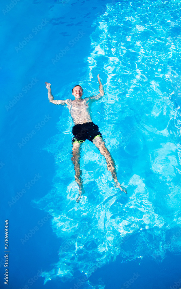 happy man is swimming in pool from top view. Summer vacation