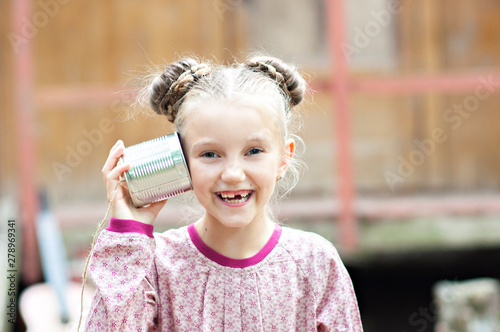 Children are testing the ancient cellular. Radio last years. Girls communicate at a distance using cans. Old technology. Children's games. Happy girls girls grandmother in the village. photo