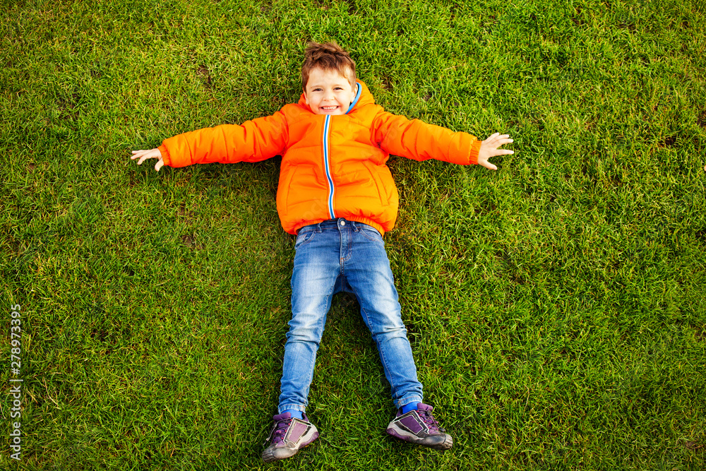 Happy little boy lying on green grass in park Happy little boy lying on green grass in park
