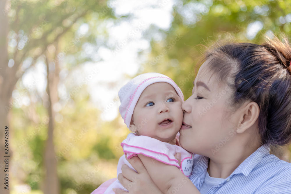 Asian women holding and kissing her little 4 months daughter outdoor. Asian women holding and kissing her little 4 months daughter outdoor.