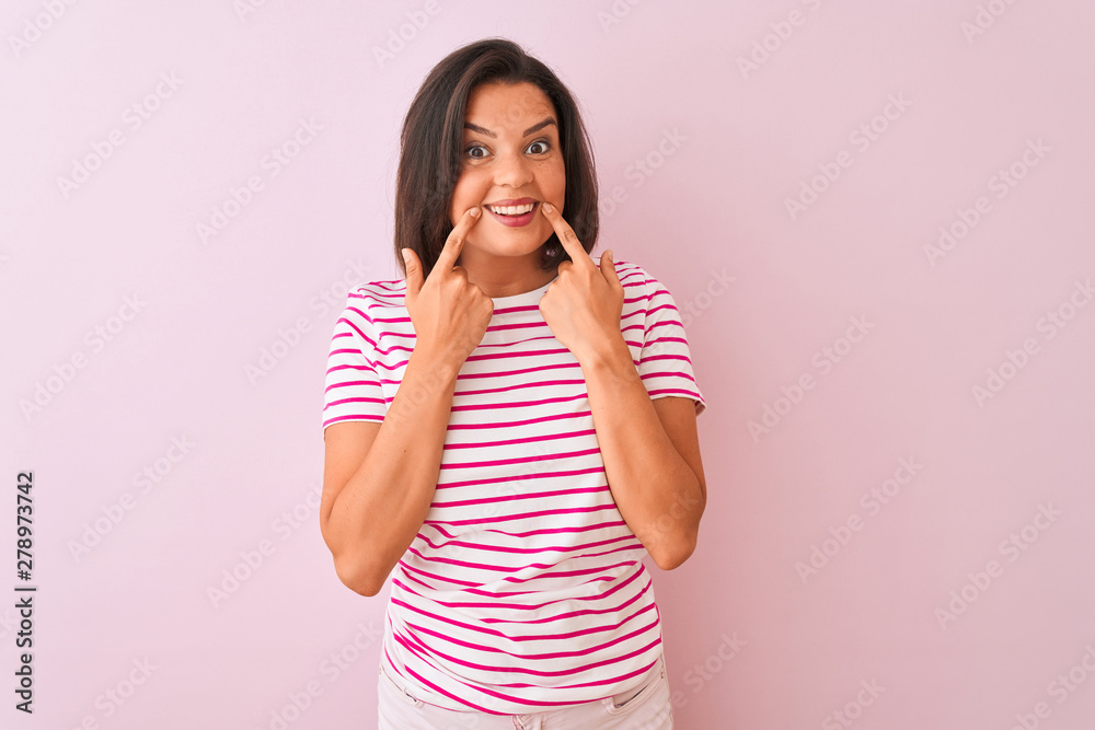 Young beautiful woman wearing striped t-shirt standing over isolated pink background Smiling with open mouth, fingers pointing and forcing cheerful smile Young beautiful woman wearing striped t-shirt standing over isolated pink background Smiling with open mouth, fingers pointing and forcing cheerful smile