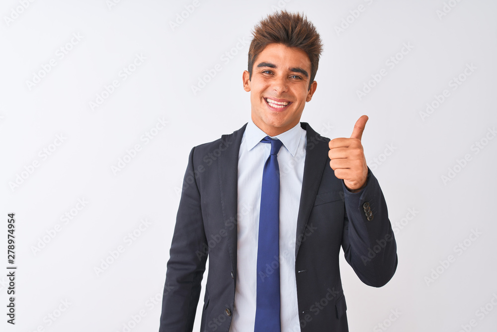 Young handsome businessman wearing suit standing over isolated white background doing happy thumbs up gesture with hand. Approving expression looking at the camera showing success. Young handsome businessman wearing suit standing over isolated white background doing happy thumbs up gesture with hand. Approving expression looking at the camera showing success.