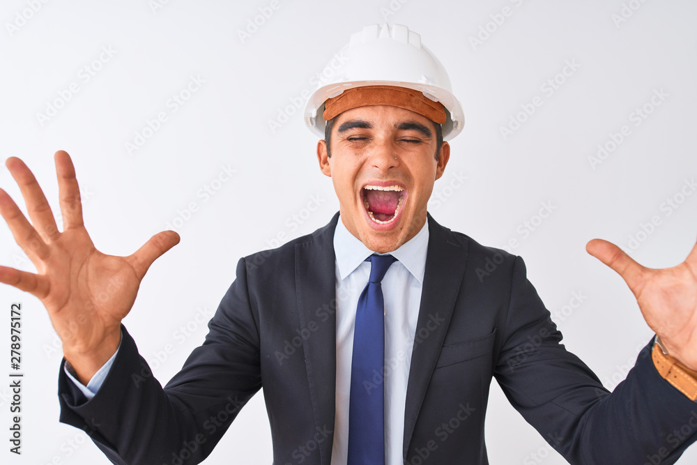 Young handsome architect man wearing suit and helmet over isolated white background celebrating mad and crazy for success with arms raised and closed eyes screaming excited. Winner concept Young handsome architect man wearing suit and helmet over isolated white background celebrating mad and crazy for success with arms raised and closed eyes screaming excited. Winner concept