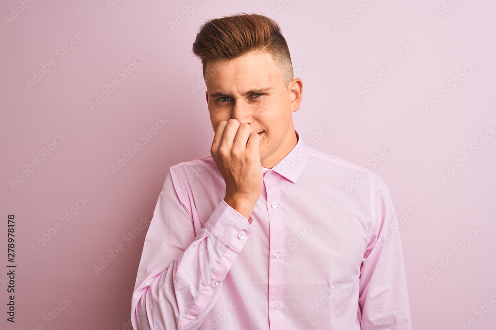 Young handsome businessman wearing elegant shirt standing over isolated pink background looking stressed and nervous with hands on mouth biting nails. Anxiety problem.