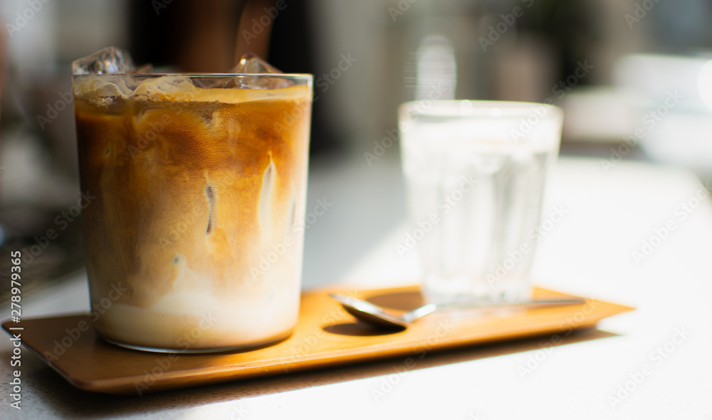 A glass of ice coffee on wooden tray A glass of ice coffee on wooden tray