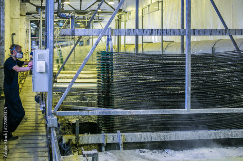 Worker pickling aluminium parts in tanks with etching acid to remove oxide cover 