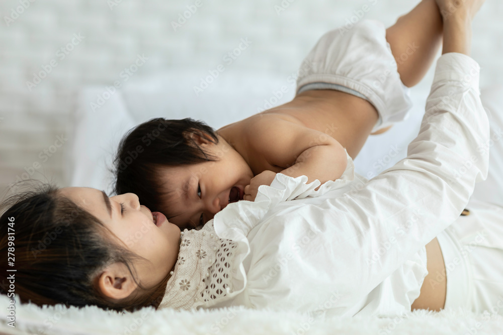 Happy Beauty mother Holding Cute Sweet Adorable Asian Baby wearing white dress smiling and playing with happiness emotional in cozy bedroom,Healthy Baby Concept,Selective Focus Happy Beauty mother Holding Cute Sweet Adorable Asian Baby wearing white dress smiling and playing with happiness emotional in cozy bedroom,Healthy Baby Concept,Selective Focus