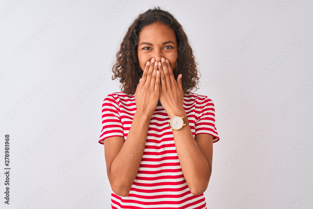 Young brazilian woman wearing red striped t-shirt standing over isolated white background laughing and embarrassed giggle covering mouth with hands, gossip and scandal concept Young brazilian woman wearing red striped t-shirt standing over isolated white background laughing and embarrassed giggle covering mouth with hands, gossip and scandal concept