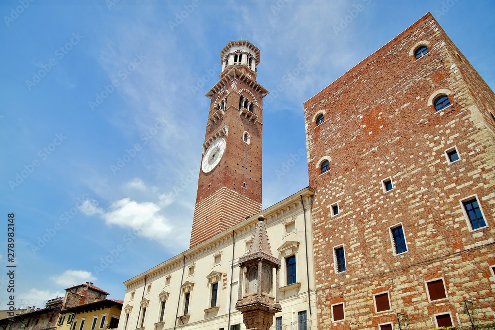 Medieval Lamberti (Torre dei Lamberti) tower XI century with clock, 84 metre and antica ancient column (1400 a.D) on Erbe Square in Verona city. Piazza delle Erbe, - Veneto, Italy